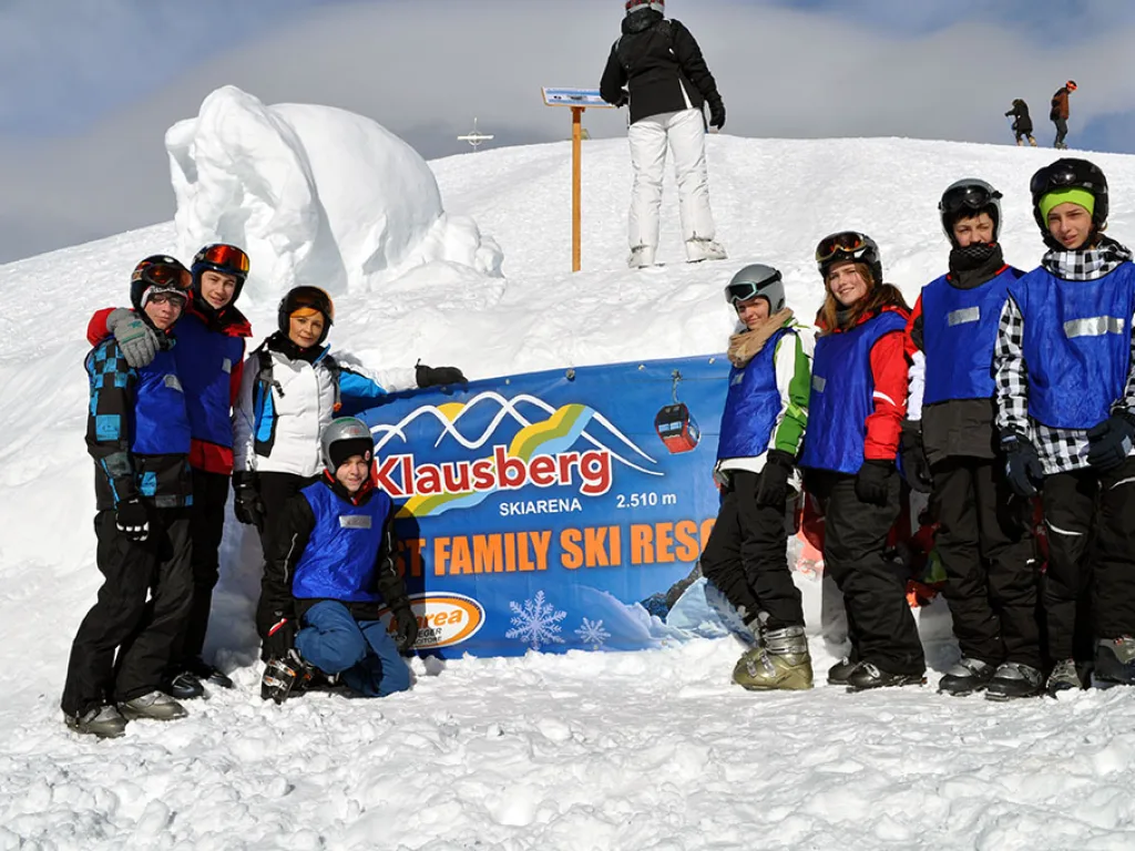 Gruppenfoto vor dem Schild des Skigebiets Klausberg.